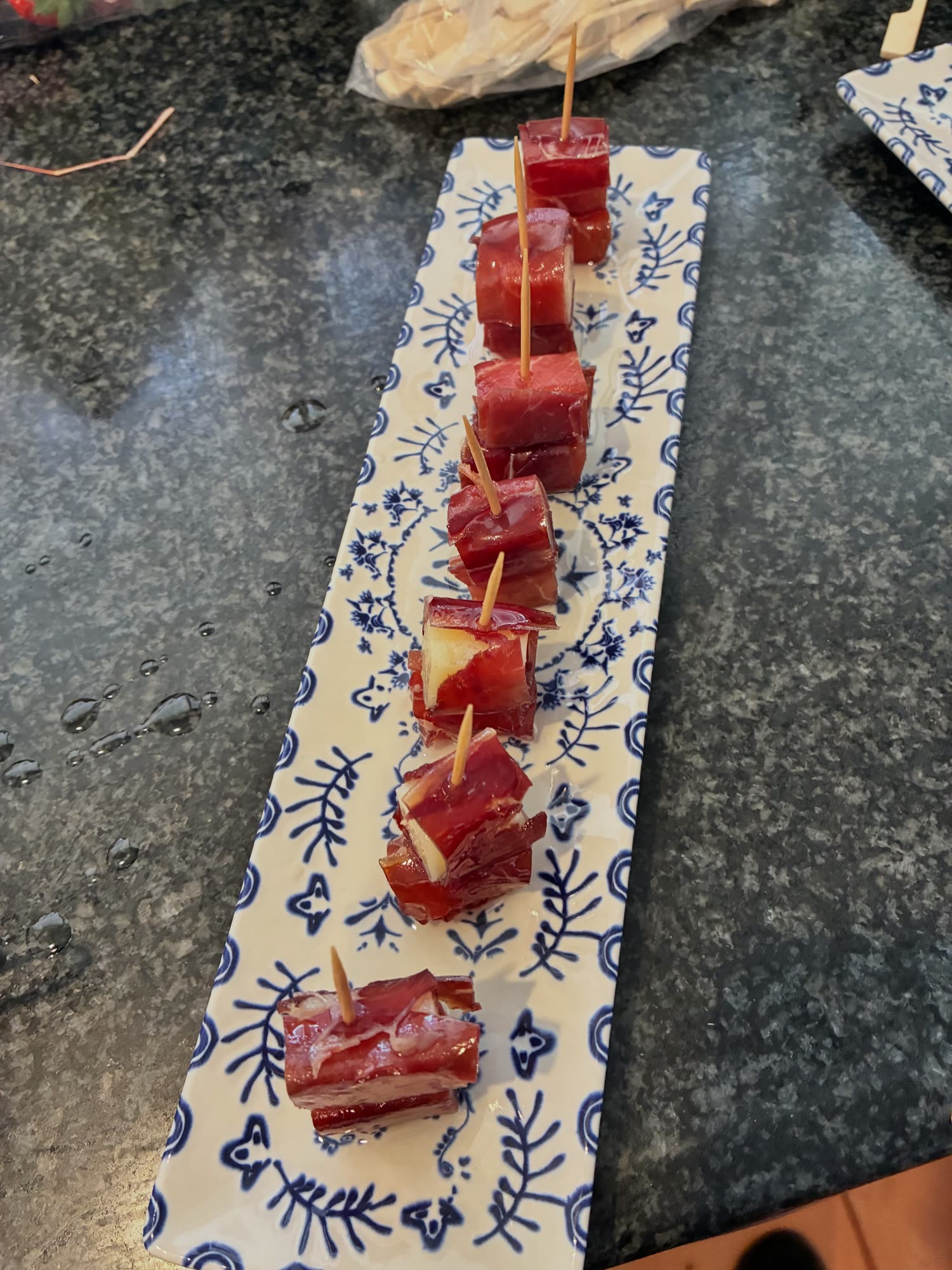 Las gildas de queso con cecina ensartadas en palillos sobre una bandeja alargada de cerámica azul y blanca
