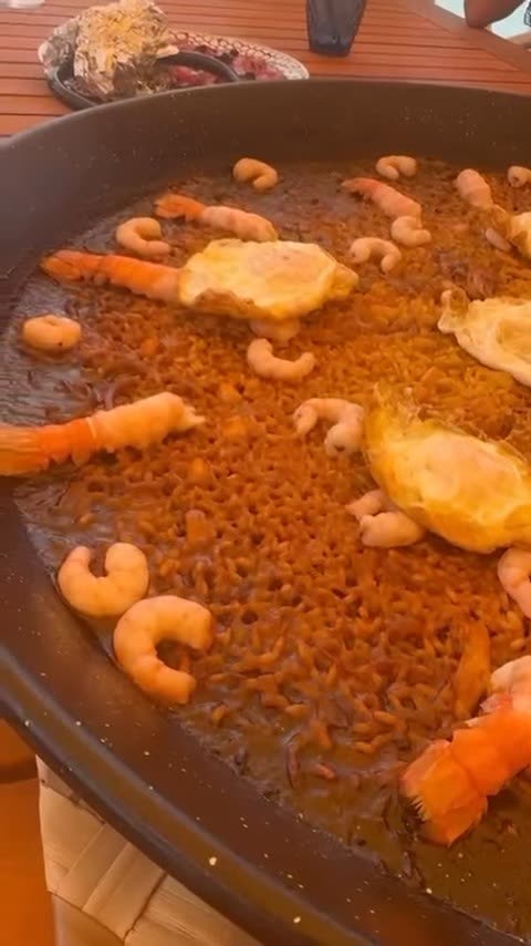 Arroz de marisco terminado en la paellera, con gambas peladas y langostinos enteros por encima